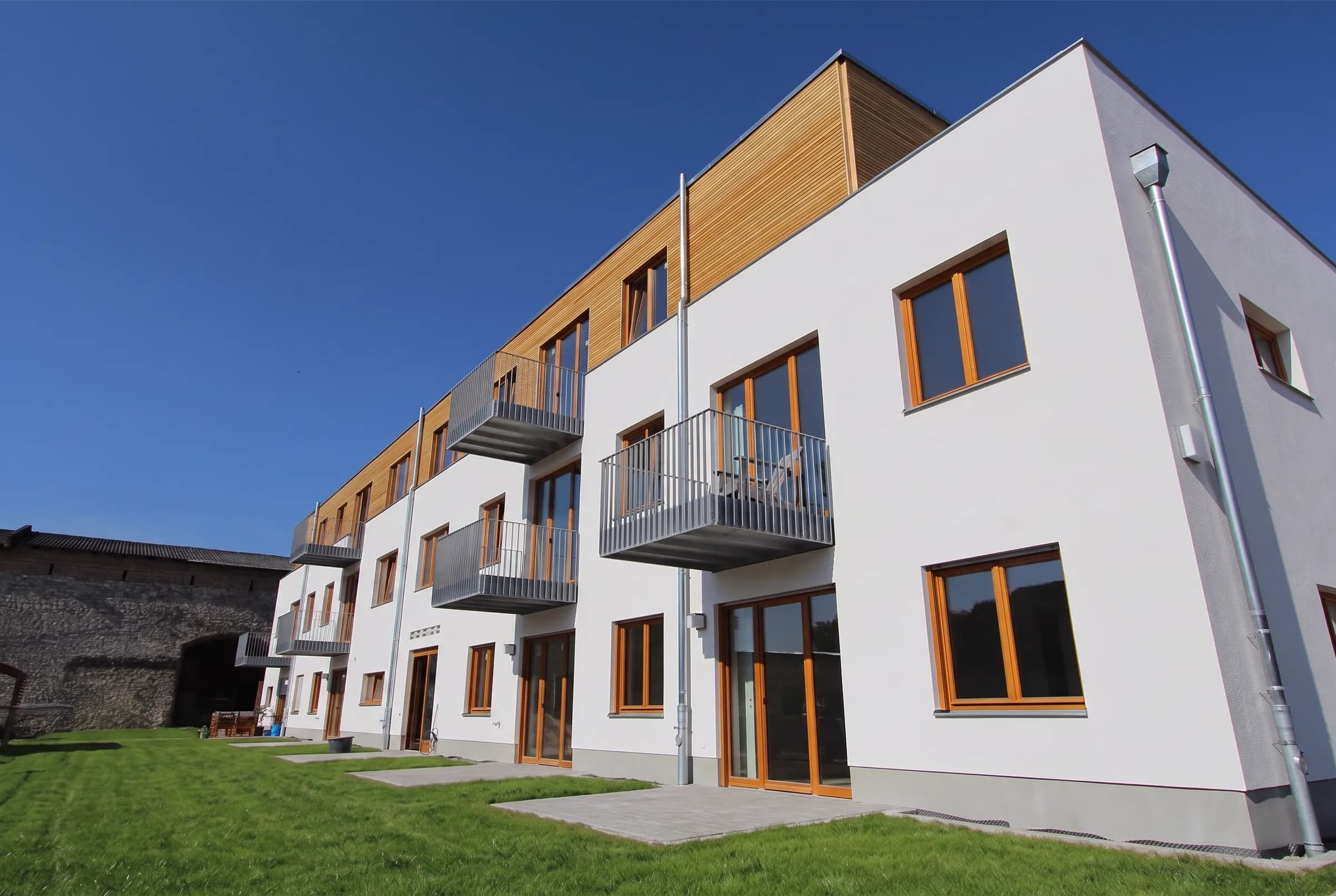 Moderner Neubau mit holzverkleidetem Obergeschoss und Balkonen