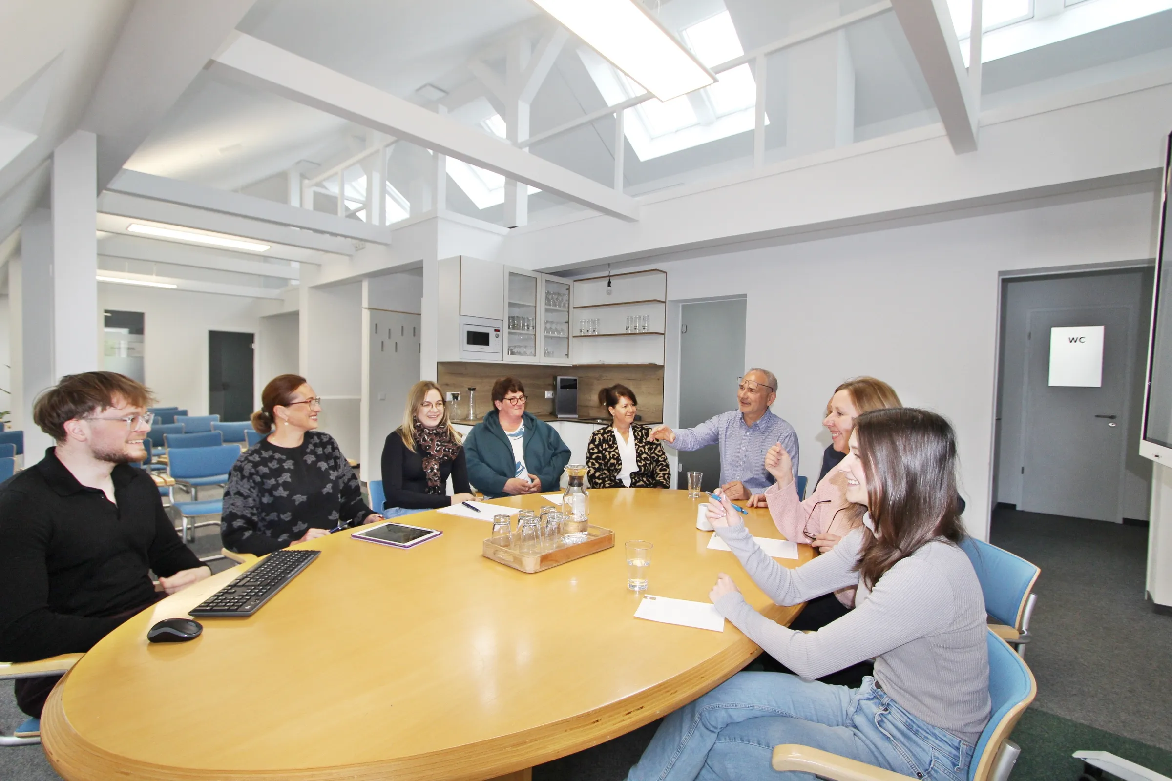 Das HAMKON-Team bei einer Besprechung am großen Tisch im Dachgeschoss-Büro